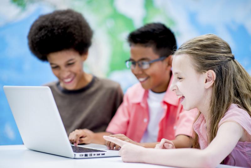 Two students sitting at a computer with teacher